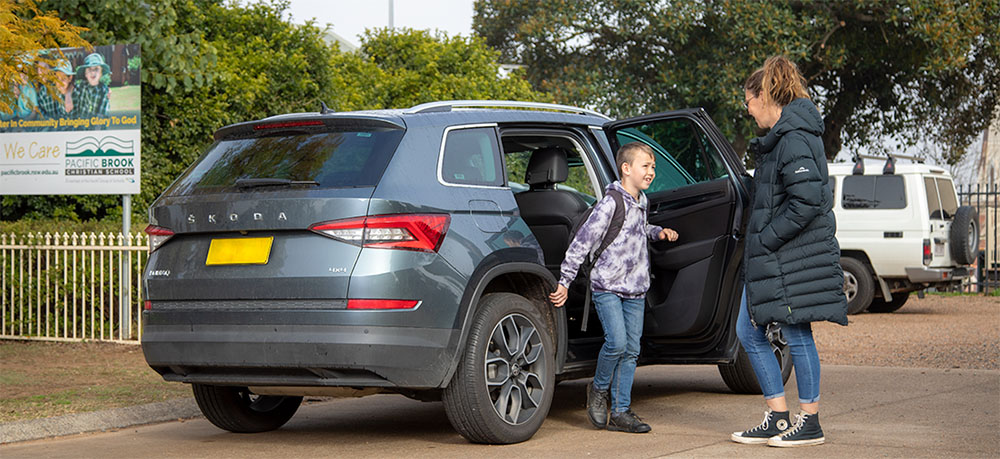 A parent dropping off their child to school via car